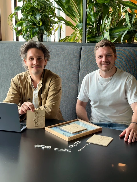 Marek Scholz und Robin Herwegh mit mehreren Reliefkarten und einem gerahmten Erinnerungsstück